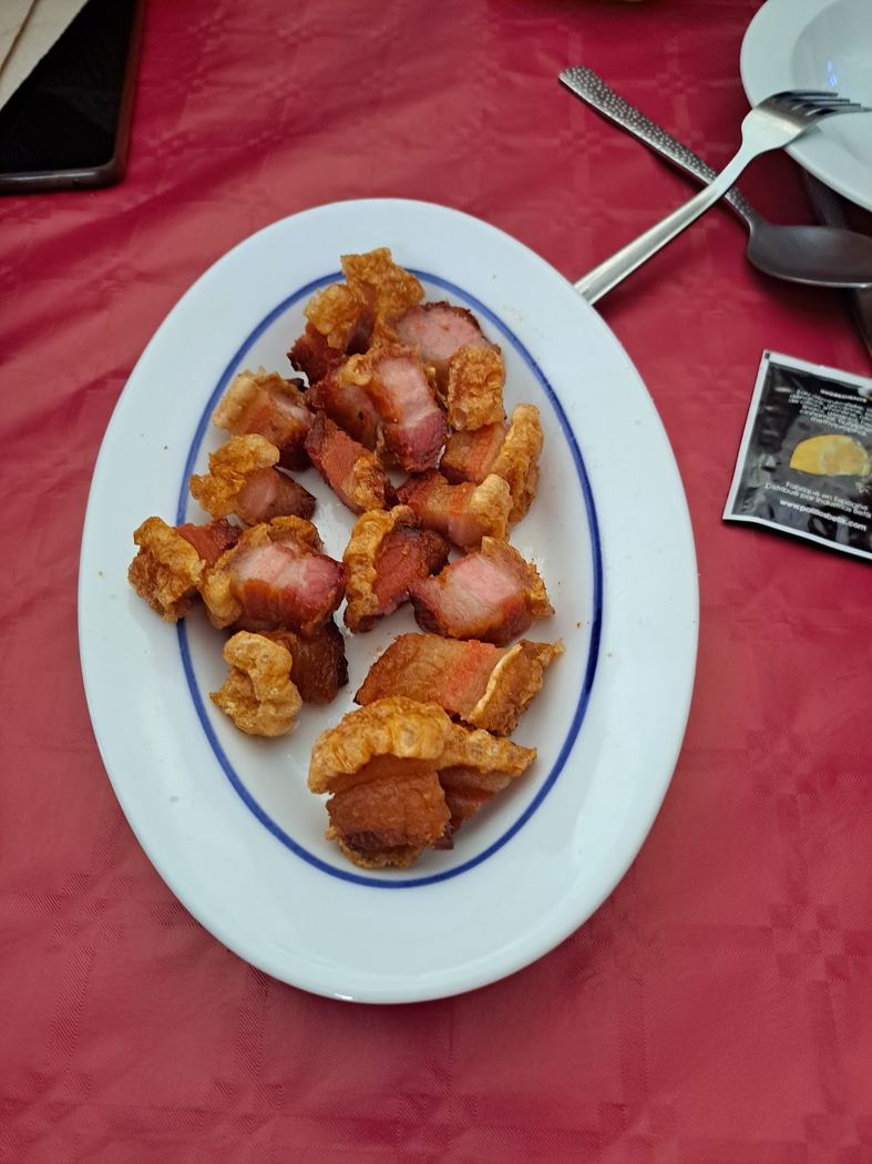 Torreznos crujientes con un toque de limón, servidos en una cazuela de barro.