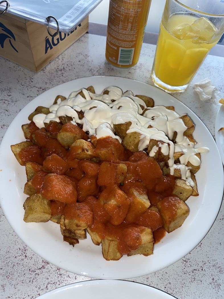 Patatas bravas con salsa brava y alioli casero, en un plato para compartir.